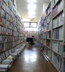 本棚の前にしゃがみこんで本を探す男性の写真