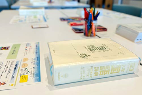 机の上に国語辞典とプリントが並んでいる