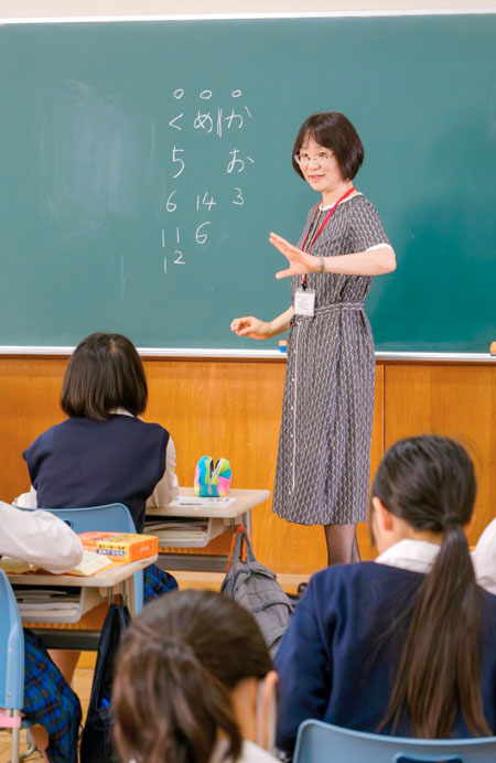 黒板の前で説明する柏野教授。「かお」「め」「くち」と書かれた下に数字が並んでいる