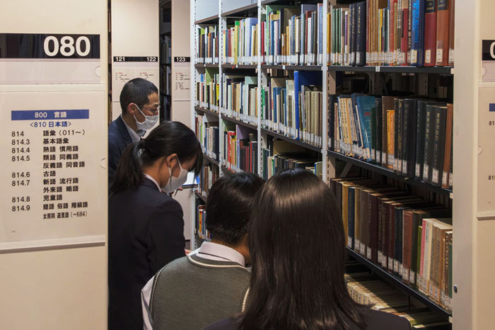 書籍がずらりと並ぶ研究図書室の書庫を興味深そうに見る生徒の皆さん